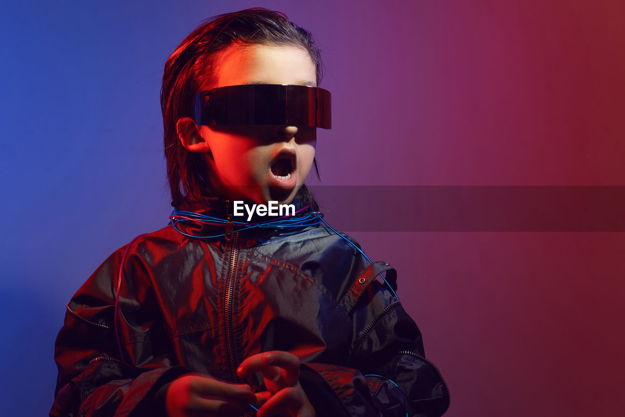 Portrait cyberpunk boy child in vr glasses in blue and red tones. game, virtual reality