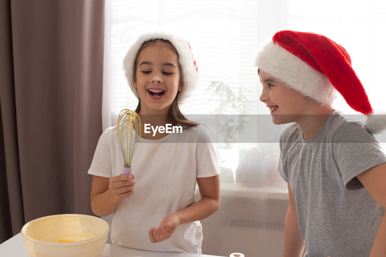 Children in red caps cheerfully cook cookies in the kitchen.