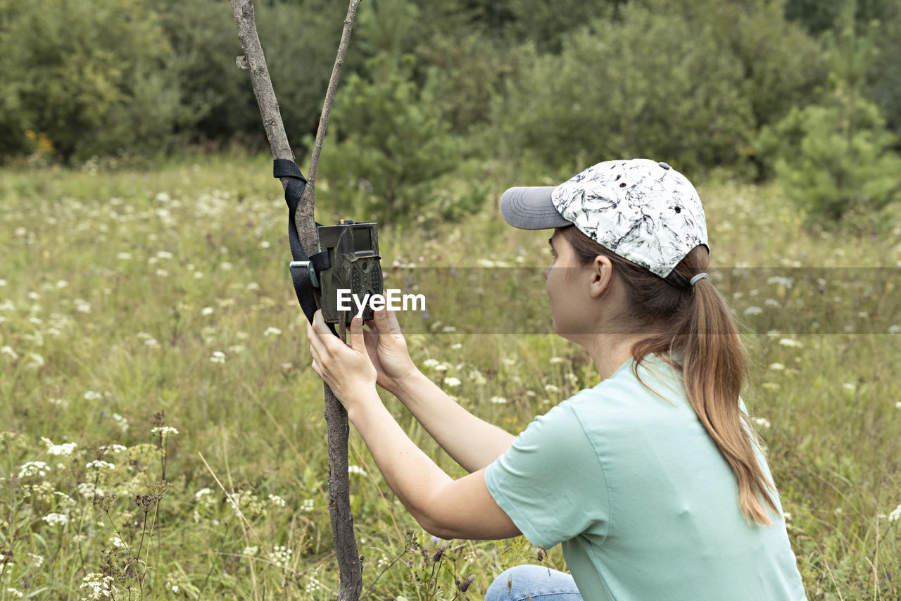 Young woman zoologist sets camera trap for observing wild rare animals to collect scientific data 