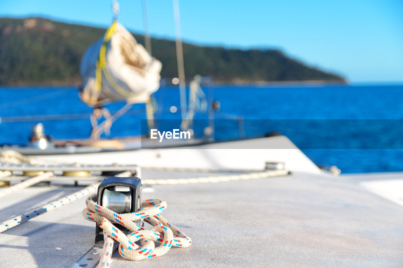 CLOSE-UP OF SAILBOATS MOORED ON SEA AGAINST SKY