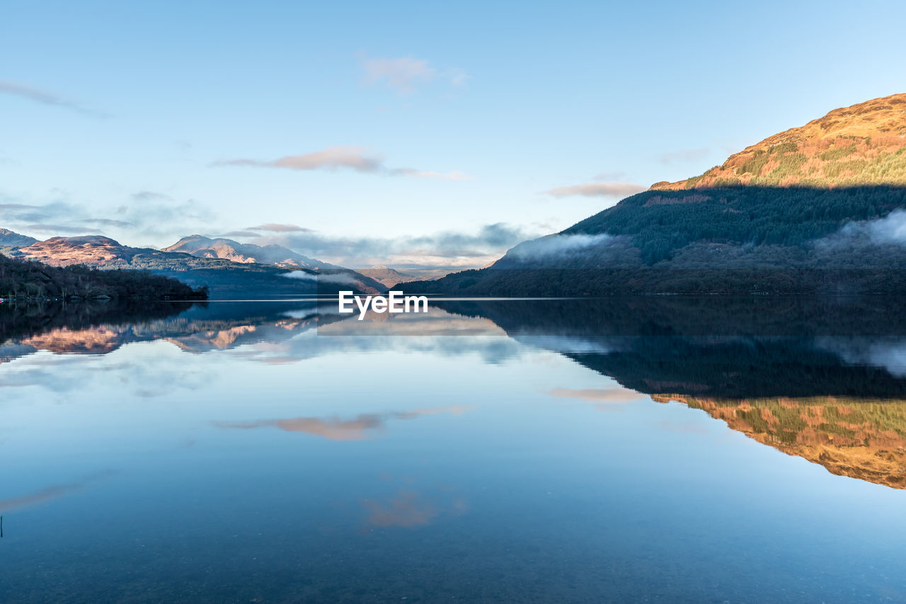 Scenic view of lake by mountains against sky