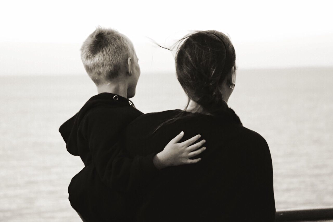 Rear view of two people overlooking calm sea