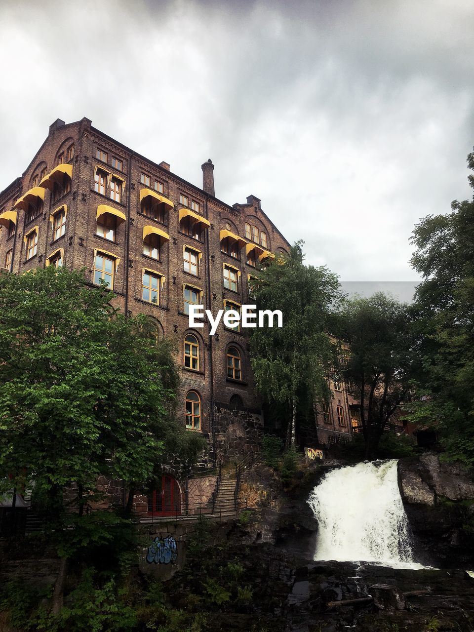 LOW ANGLE VIEW OF BUILDING BY TREES AGAINST SKY