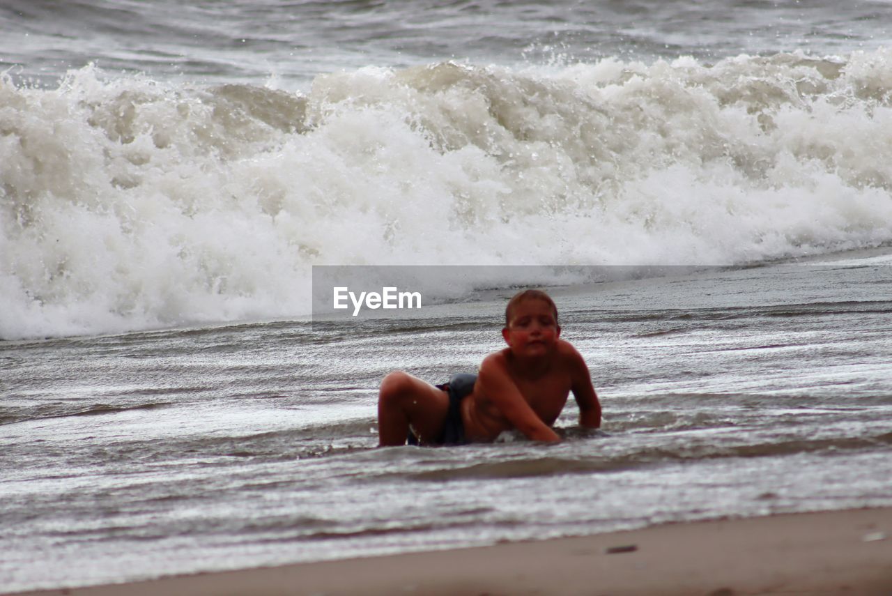 FULL LENGTH OF SHIRTLESS BOY AT BEACH