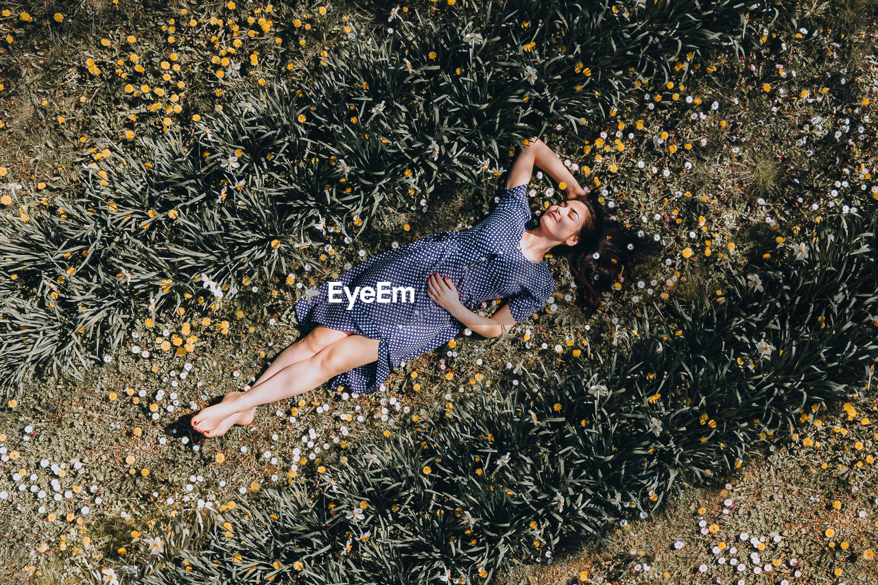 High angle view of woman lying down on field with flowers 