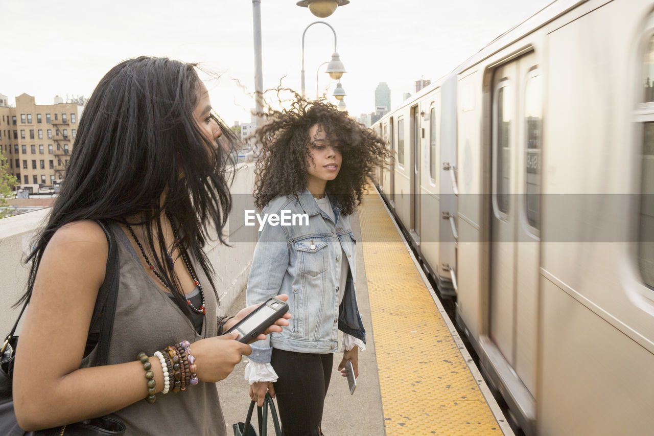 Young women waiting at a train station in queens, new york