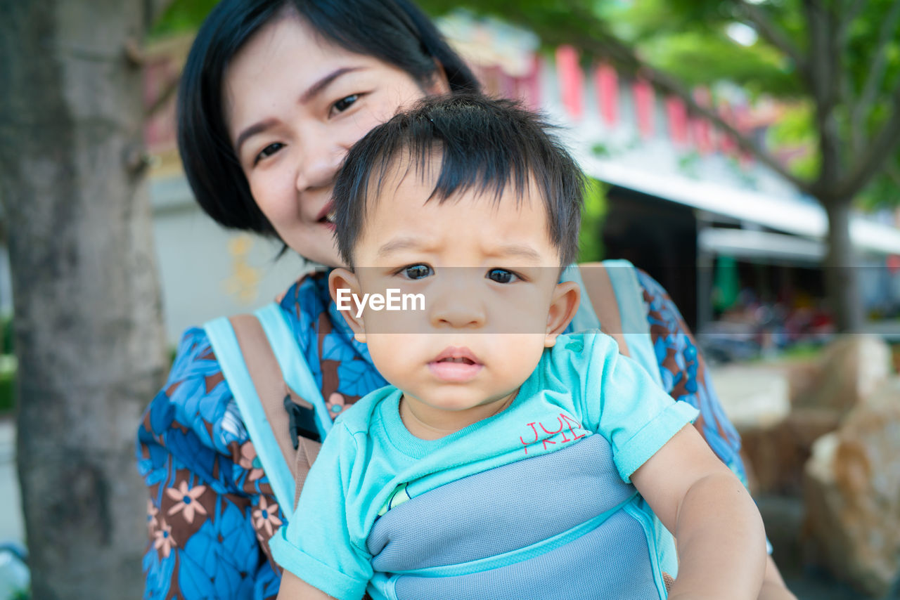 Portrait of cute smiling son with mother sitting outdoors