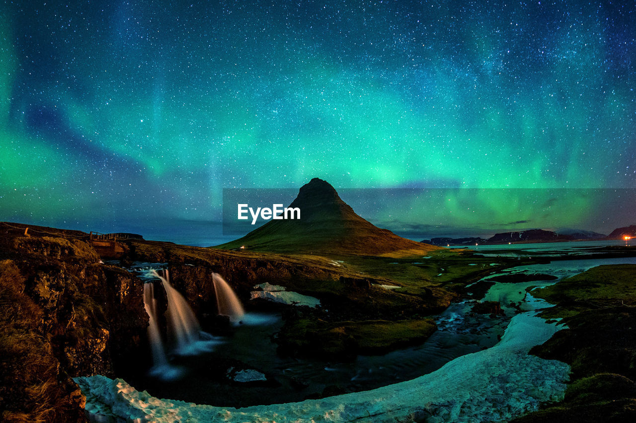 Scenic view of mountain and waterfall against sky at night