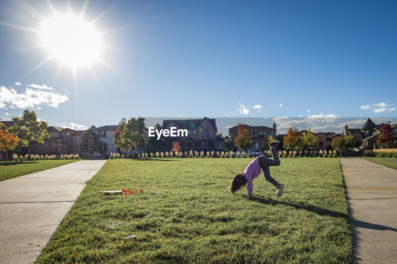 Playful girl playing on grass during sunny day at park