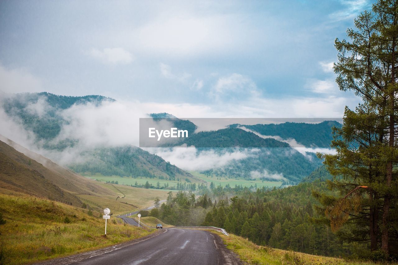 Road leading towards mountains against sky