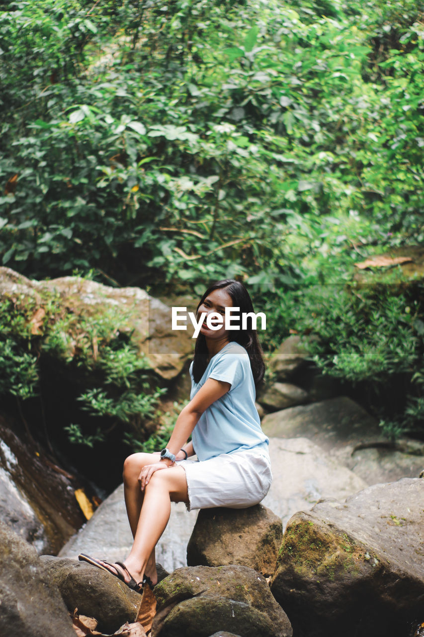 Woman sitting on rock in forest