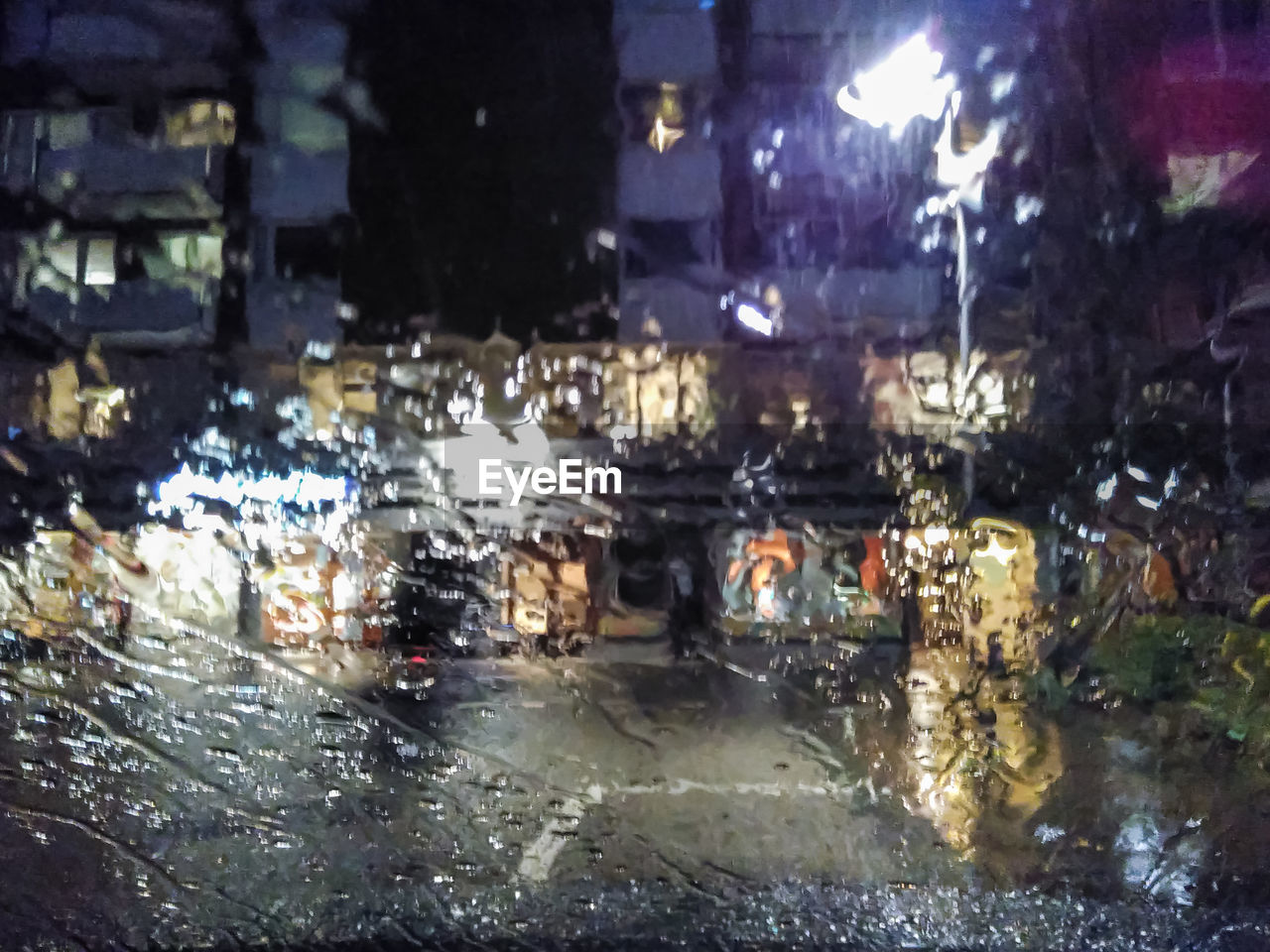 Illuminated city seen through wet windshield at night