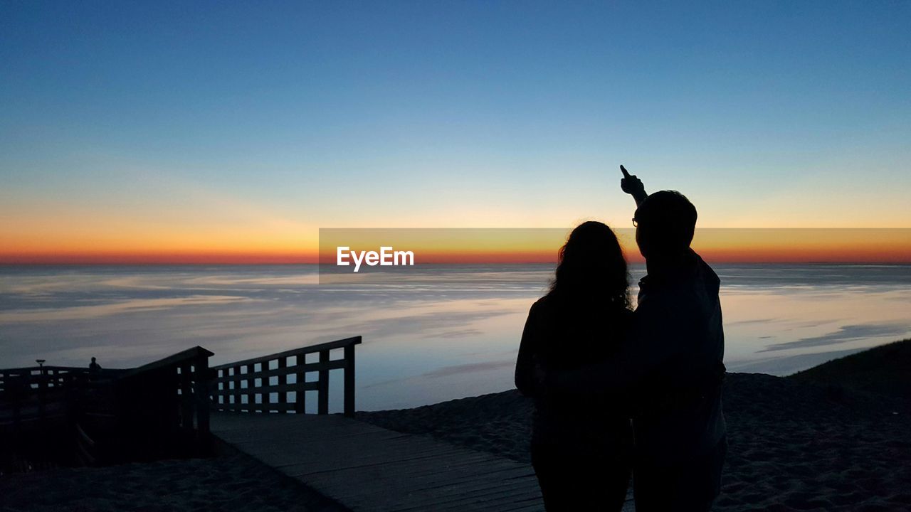 Silhouette of young couple enjoying view of lake michigan at sunset from sleeping bear dunes 