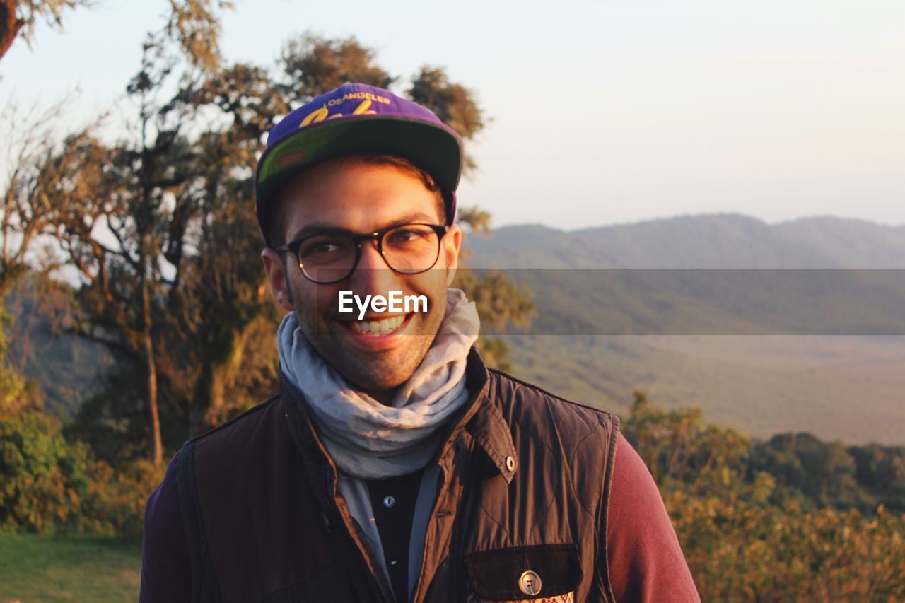 PORTRAIT OF YOUNG MAN STANDING ON MOUNTAIN