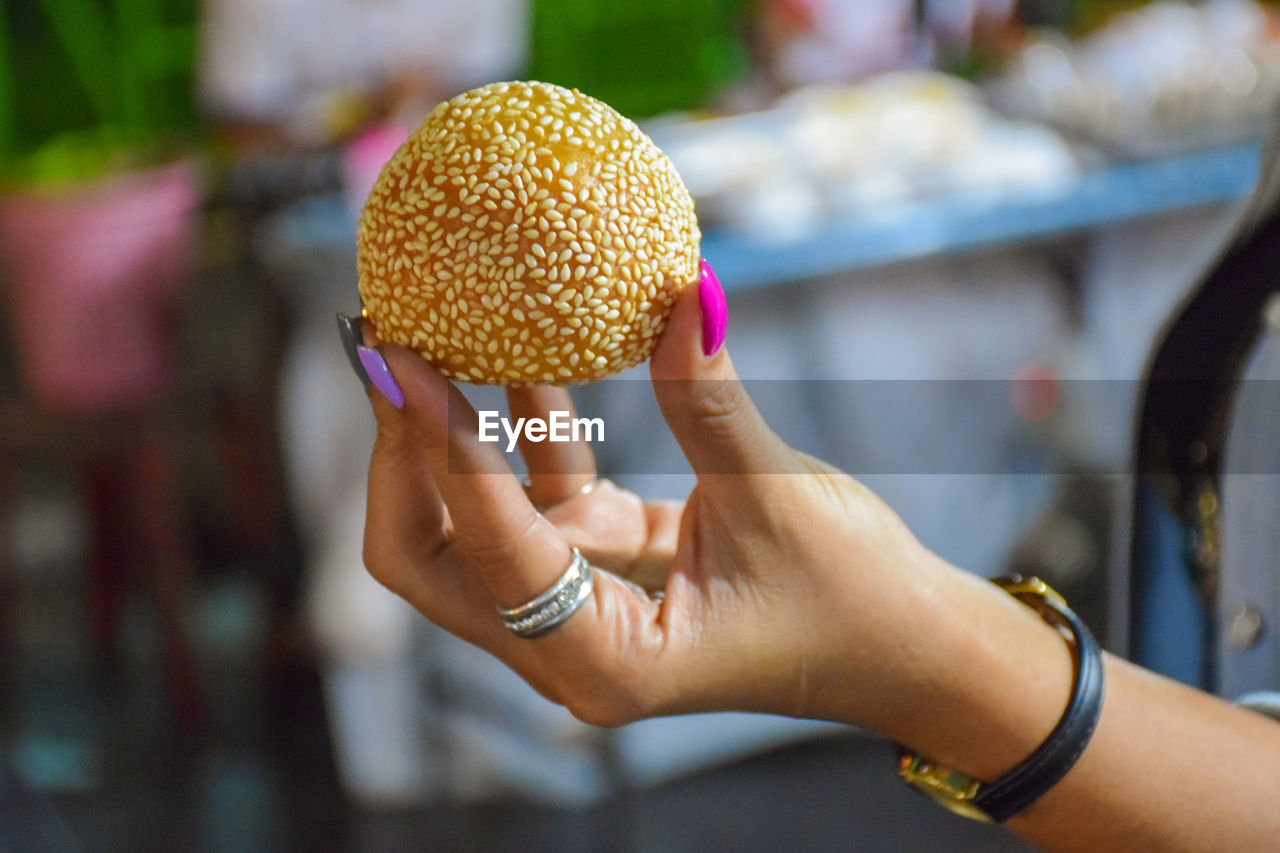 Cropped hand of woman holding sweet food outdoors