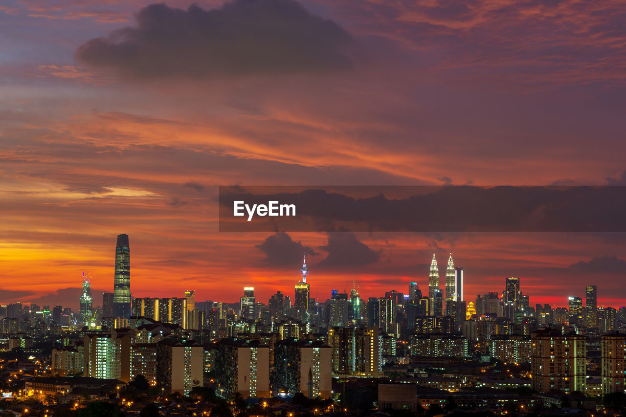 Illuminated cityscape against sky during sunset