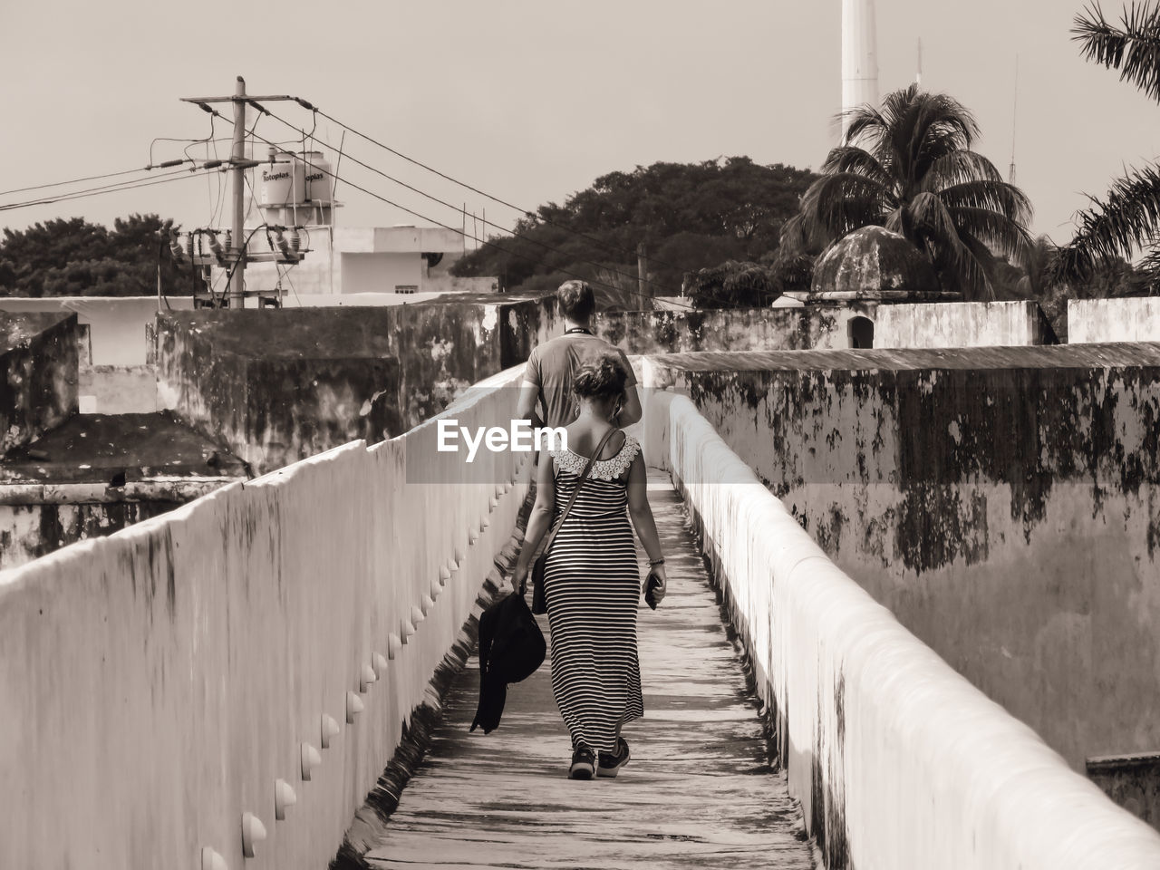 Rear view of woman on footbridge against sky