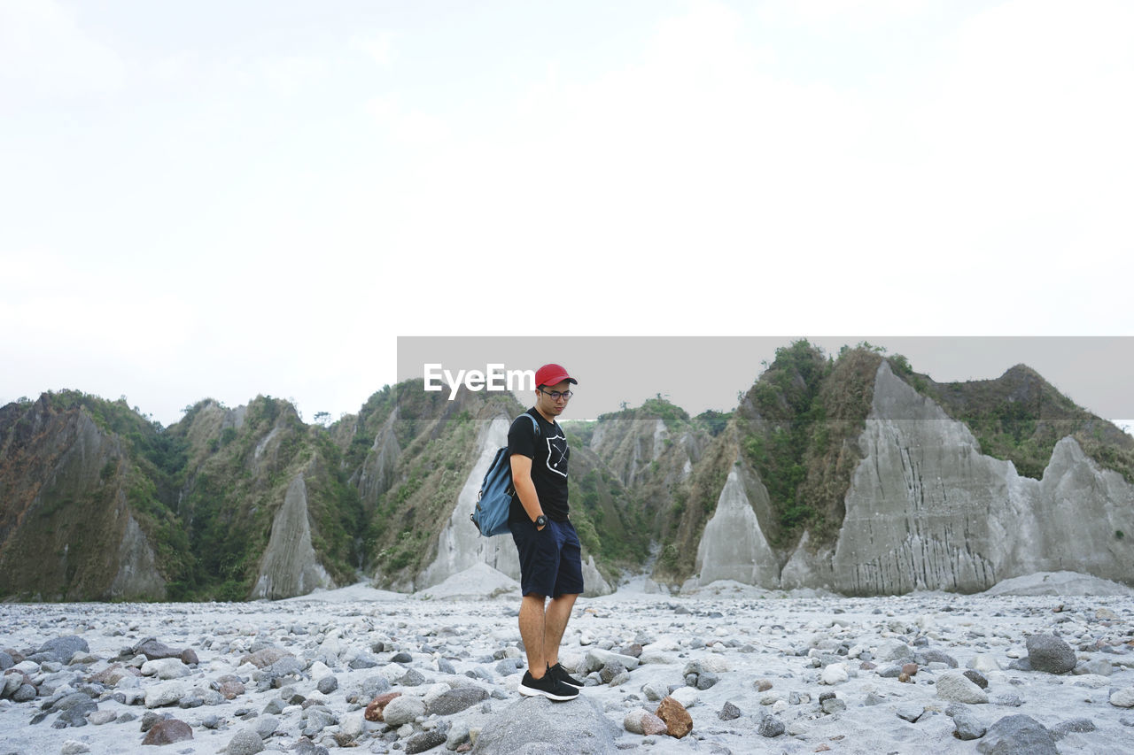 Young man standing on rocky beach