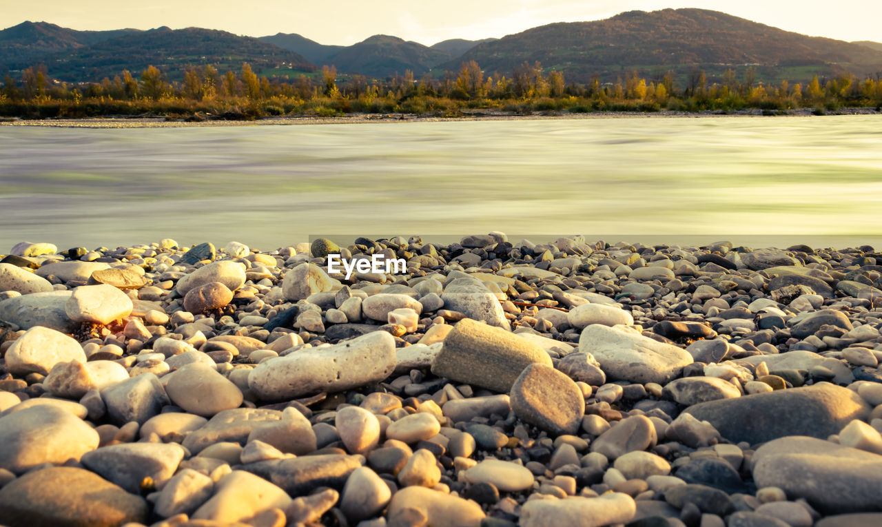 Reflections of the sun on the rippling colorful waters of the piave river at sunset. 