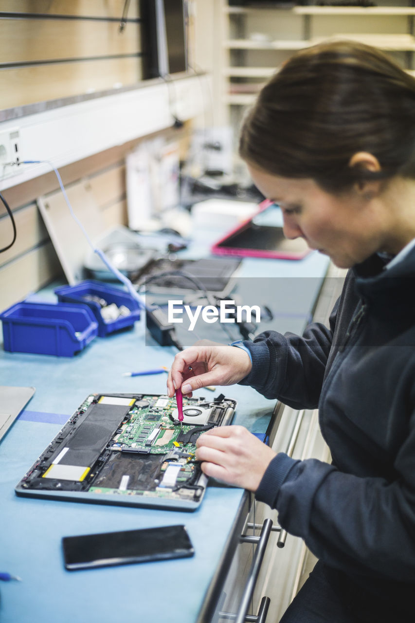 Mature female engineer repairing equipment in computer store