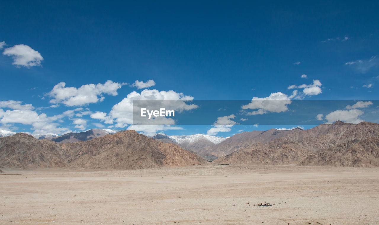 Scenic view of landscape and mountains against blue sky
