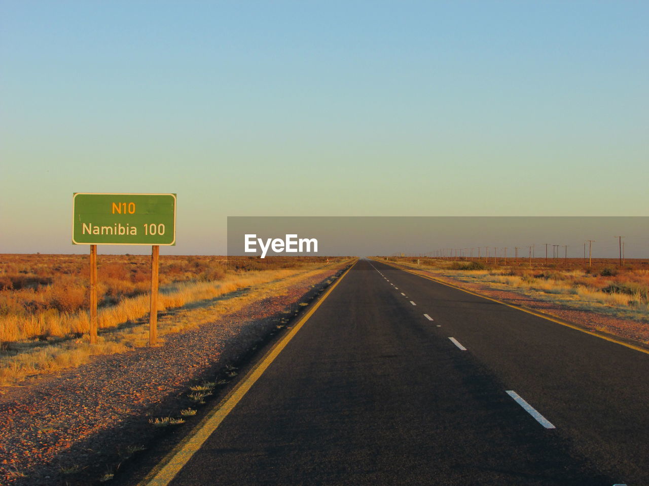 Information sign by road on landscape against clear sky