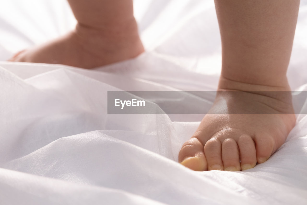 bed, adult, women, indoors, bedroom, human leg, close-up, human foot, one person, relaxation, limb, low section, human limb, linen, furniture, domestic room, textile, female, white, hand, lifestyles, baby, barefoot, young adult, sheet, healthcare and medicine, child, lying down