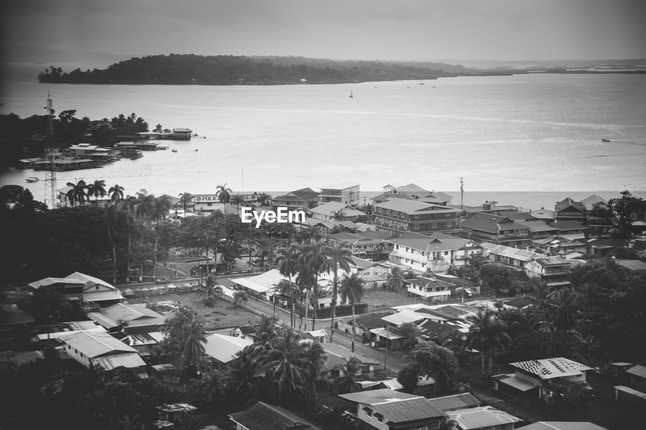 High angle view of cityscape in front of sea against sky