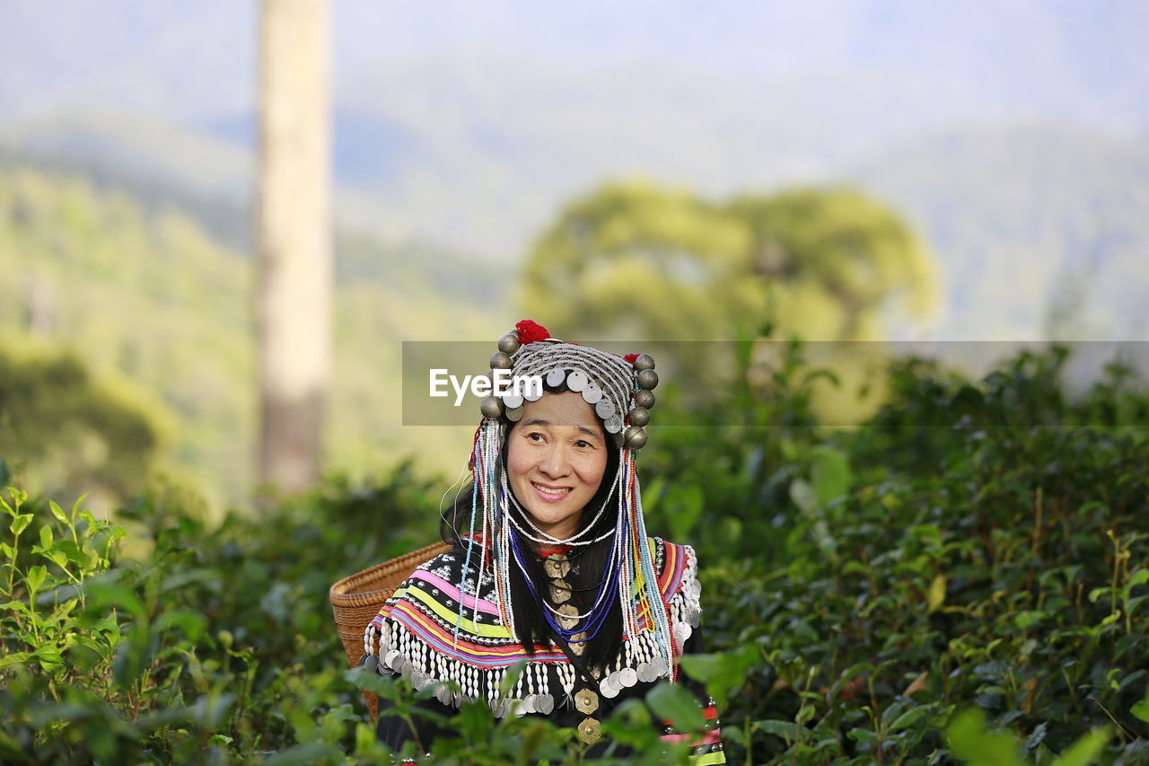 PORTRAIT OF SMILING YOUNG WOMAN IN TRADITIONAL CLOTHING