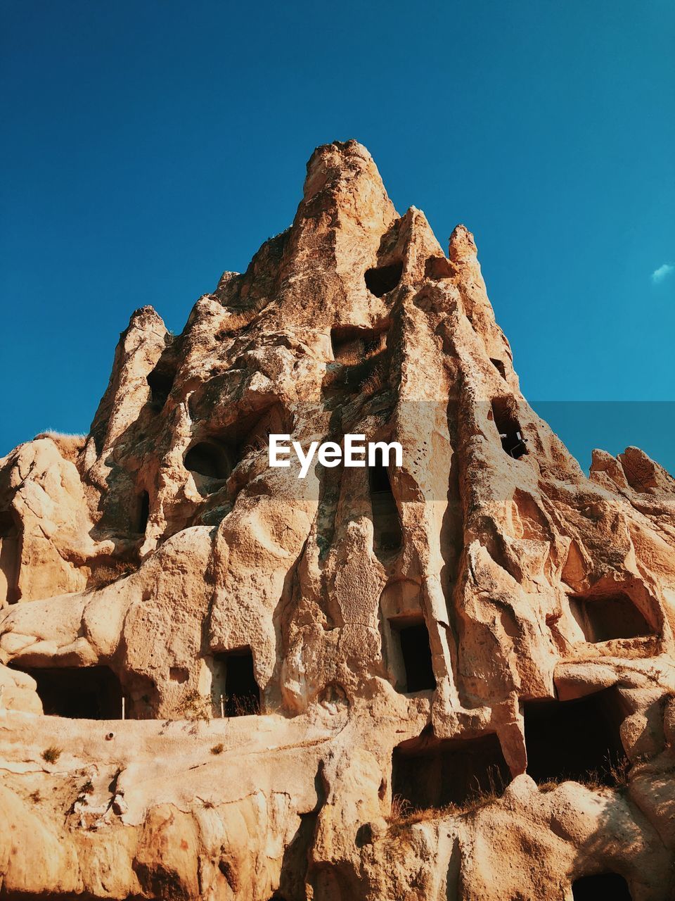 Low angle view of rock formation against clear blue sky