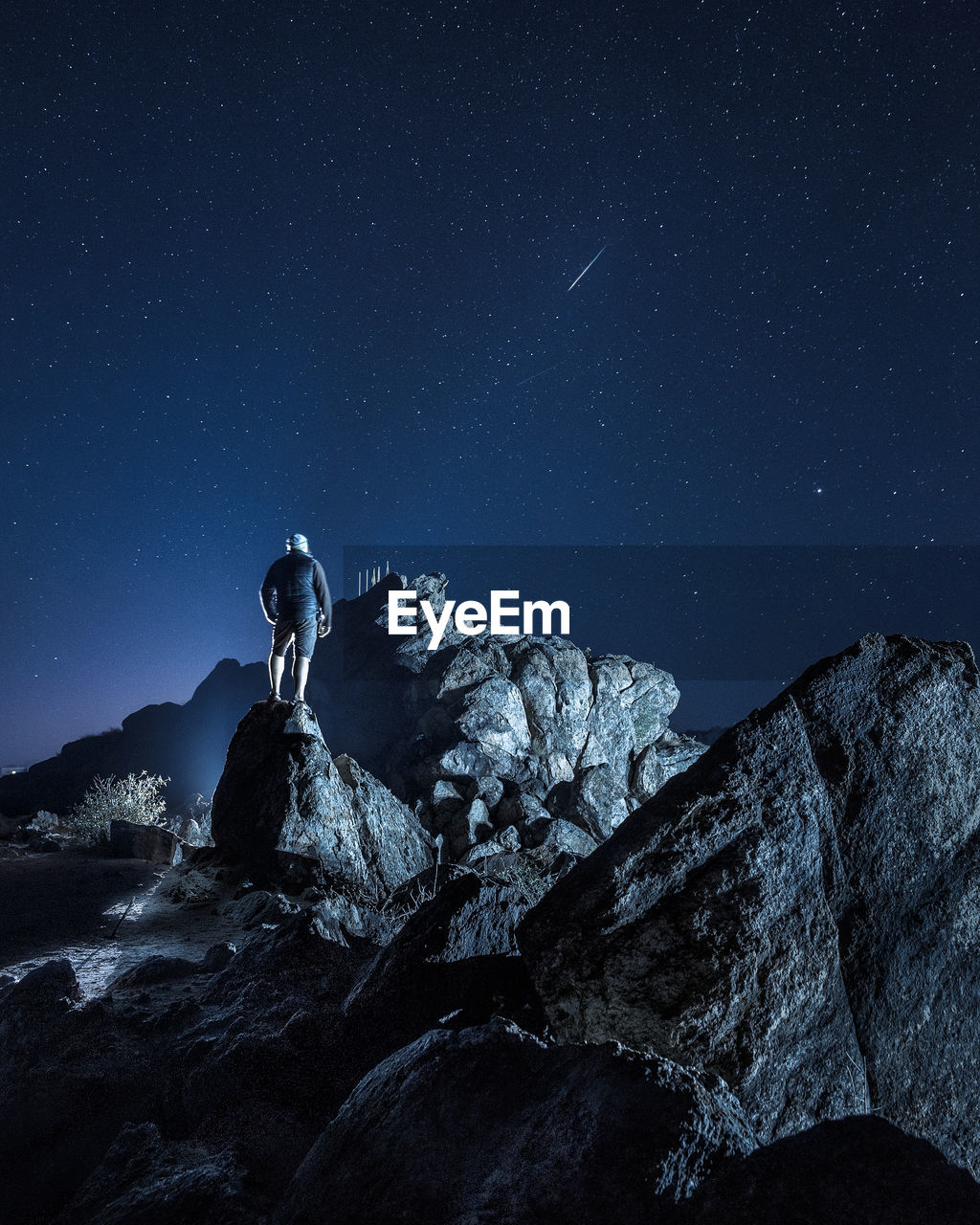 Man standing on rock against sky at night