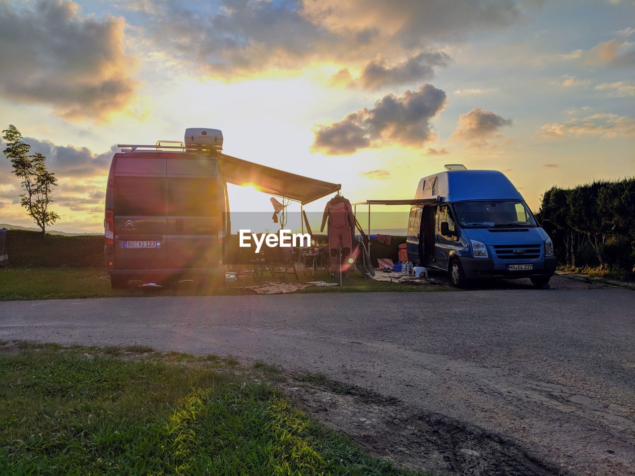 VEHICLES ON ROAD AGAINST SKY DURING SUNSET