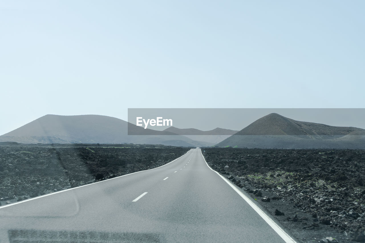 EMPTY ROAD LEADING TOWARDS MOUNTAIN AGAINST CLEAR SKY