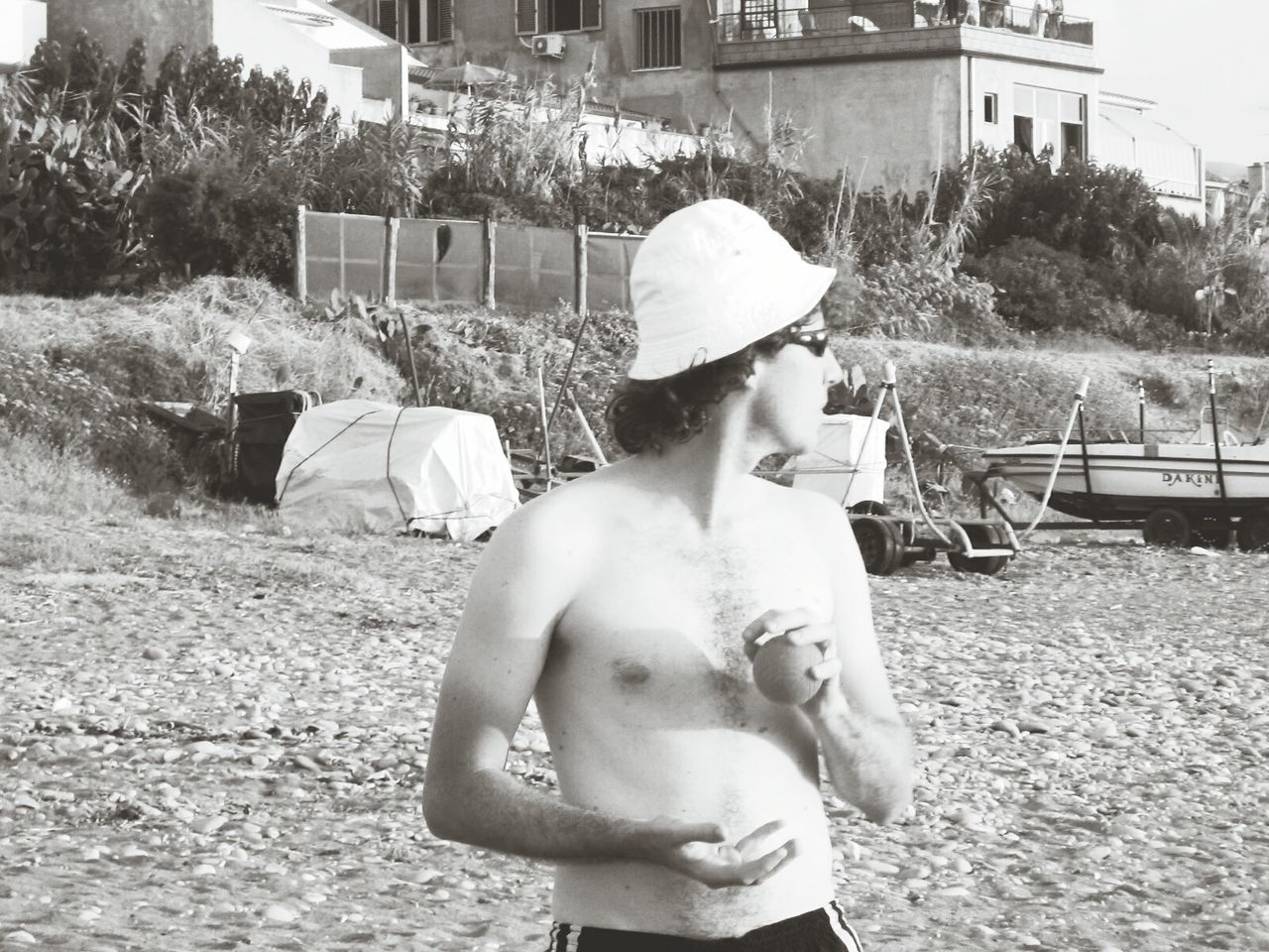 Shirtless man playing with ball while standing on beach