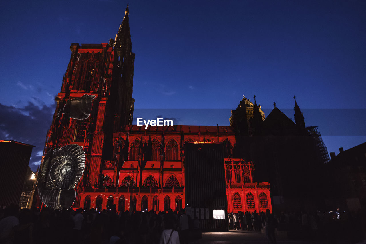 LOW ANGLE VIEW OF ILLUMINATED BUILDINGS AT DUSK