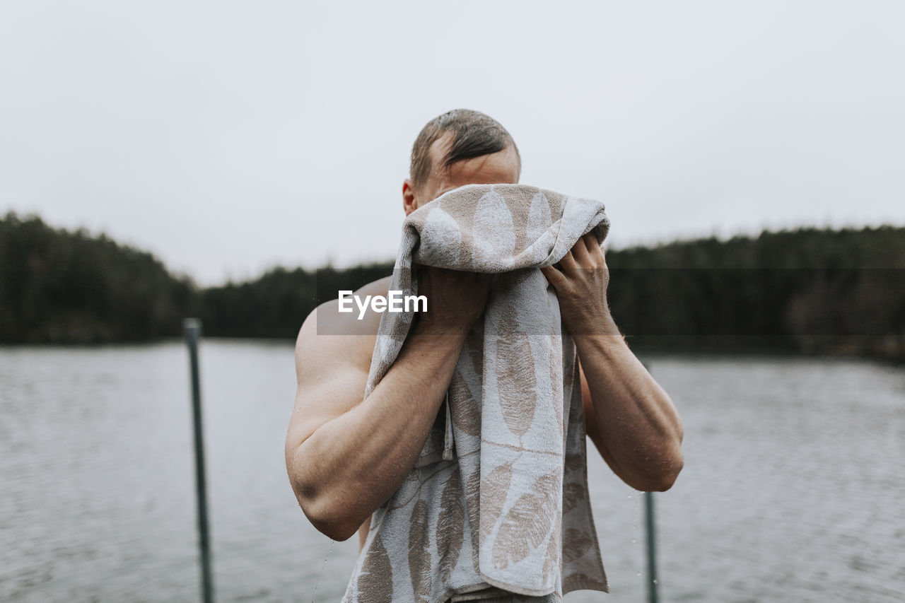 Man at lake drying himself with towel