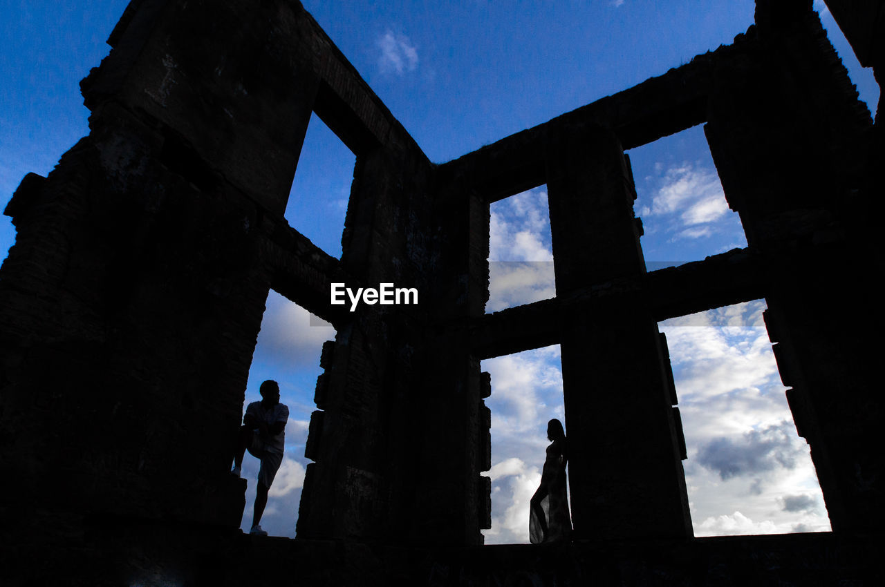 LOW ANGLE VIEW OF SILHOUETTE BUILDING AGAINST BLUE SKY