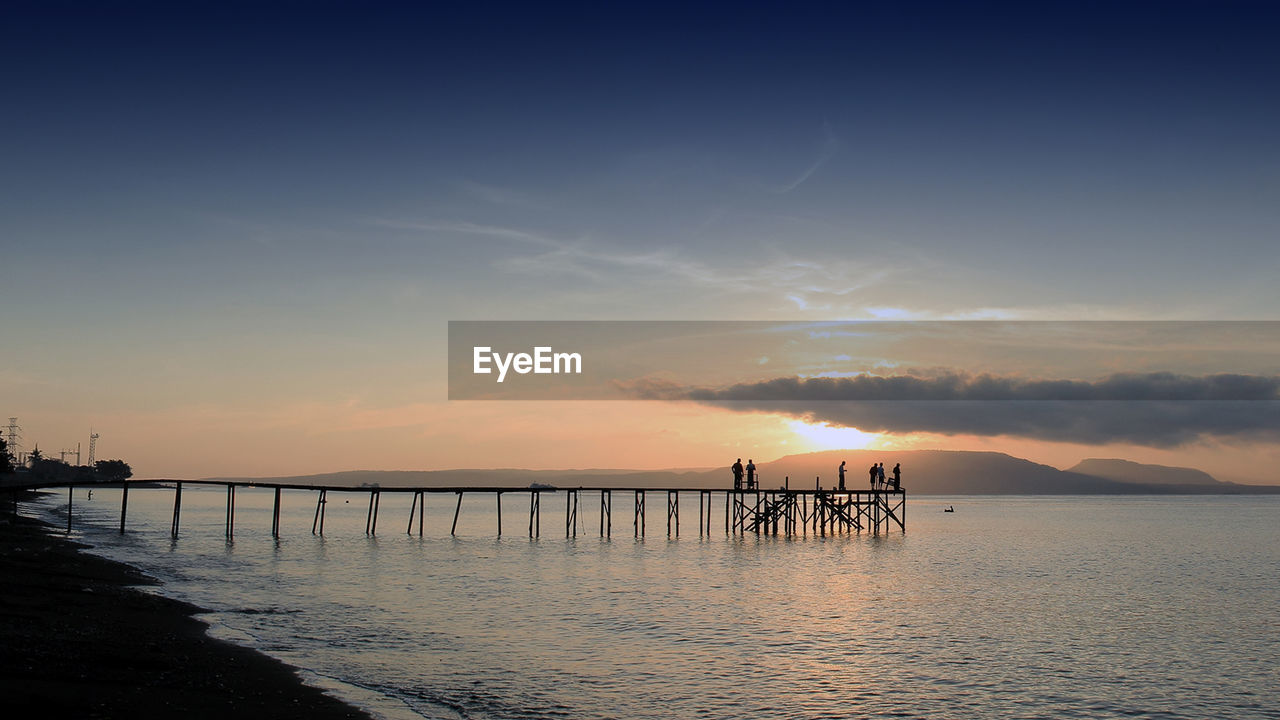 Silhouette pier over sea against sky during sunset