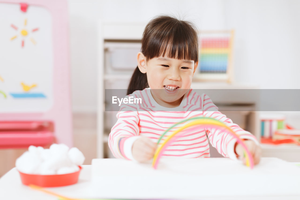 Young girl making rainbow craft using pipe cleaner at home