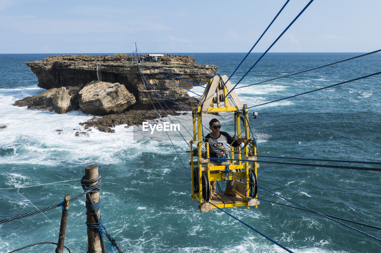 Person in overhead cable car above sea