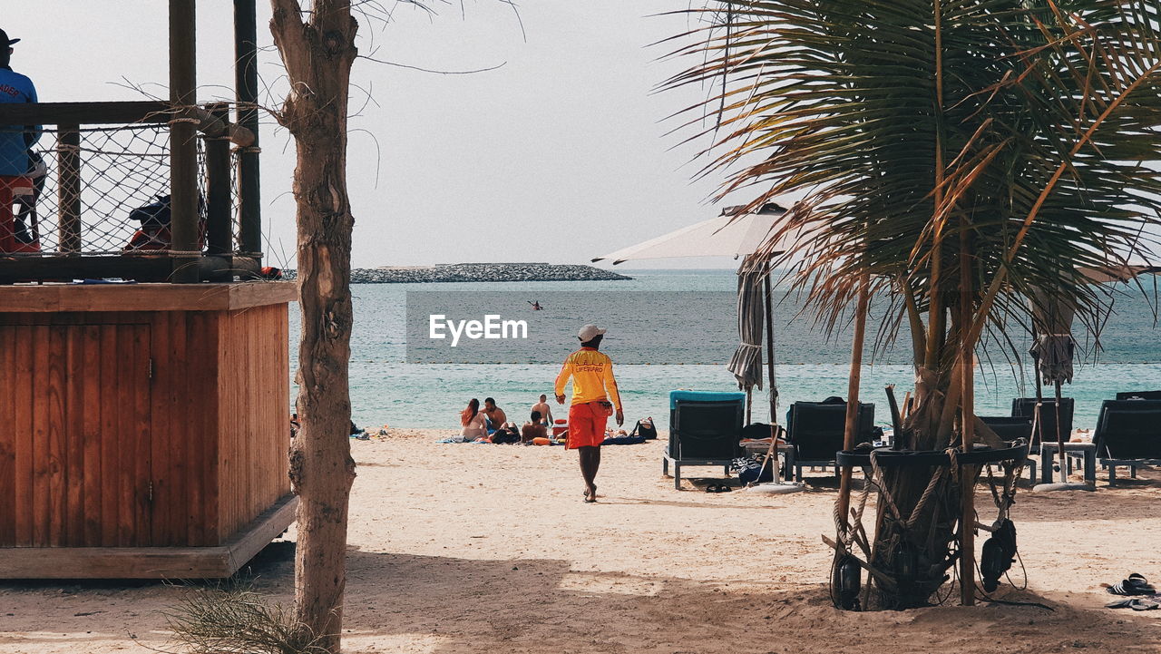 REAR VIEW OF PEOPLE ON BEACH