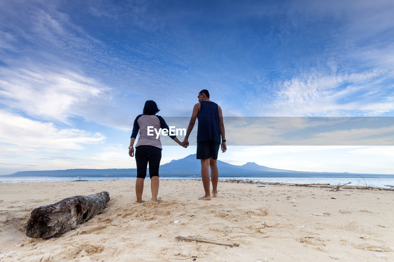 REAR VIEW OF MEN AND DOG ON BEACH