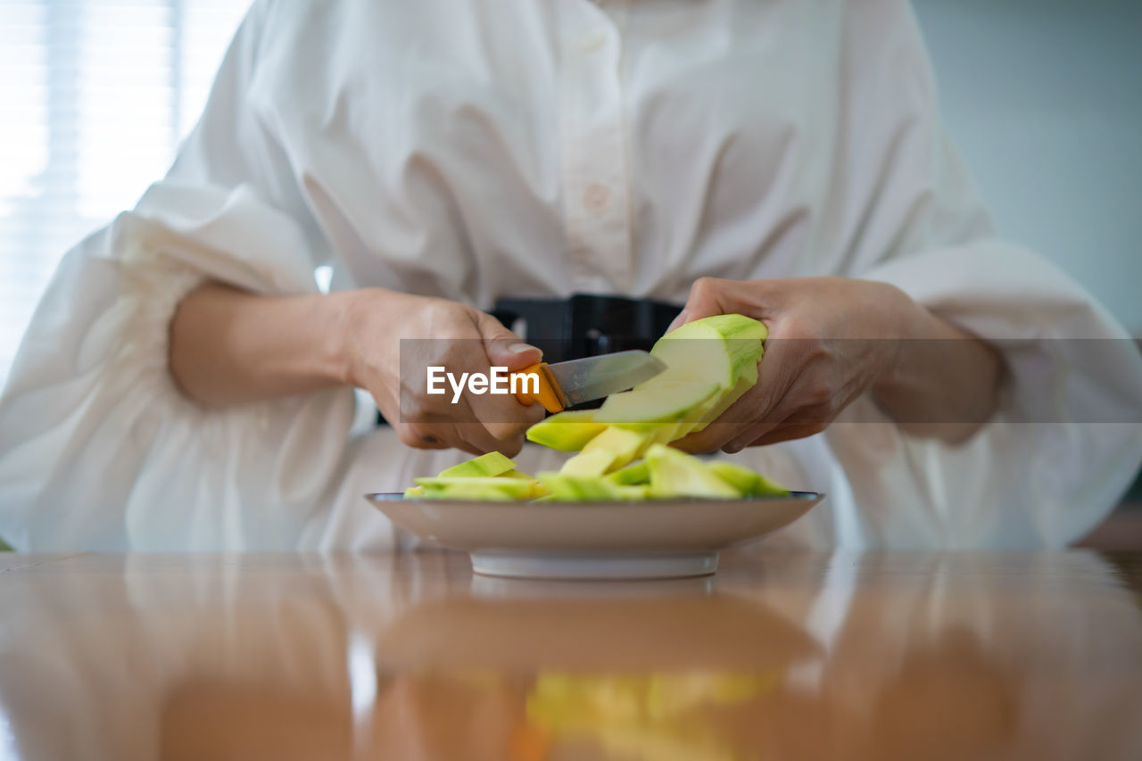 MIDSECTION OF MAN EATING FOOD IN KITCHEN