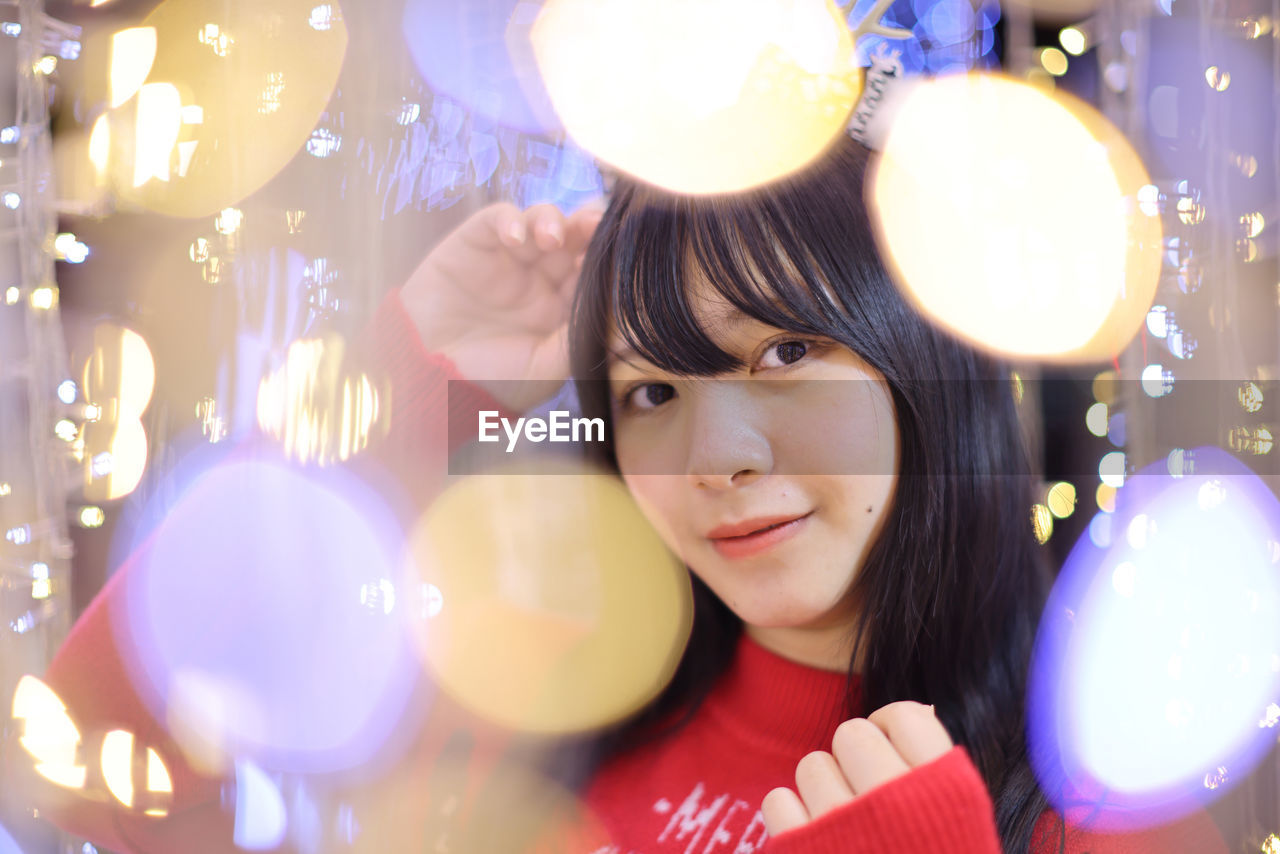 portrait of young woman holding illuminated christmas tree