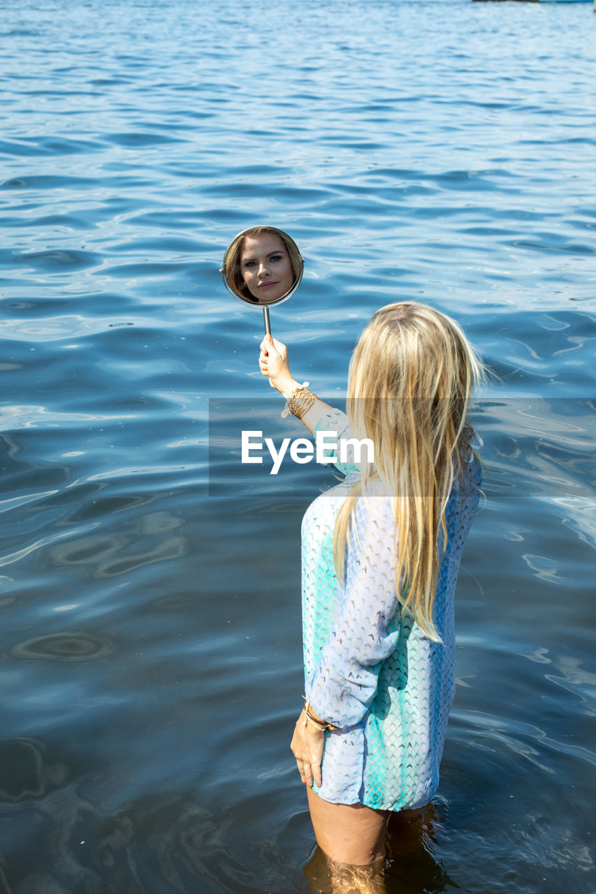 GIRL HOLDING WOMAN STANDING IN WATER AT SHORE