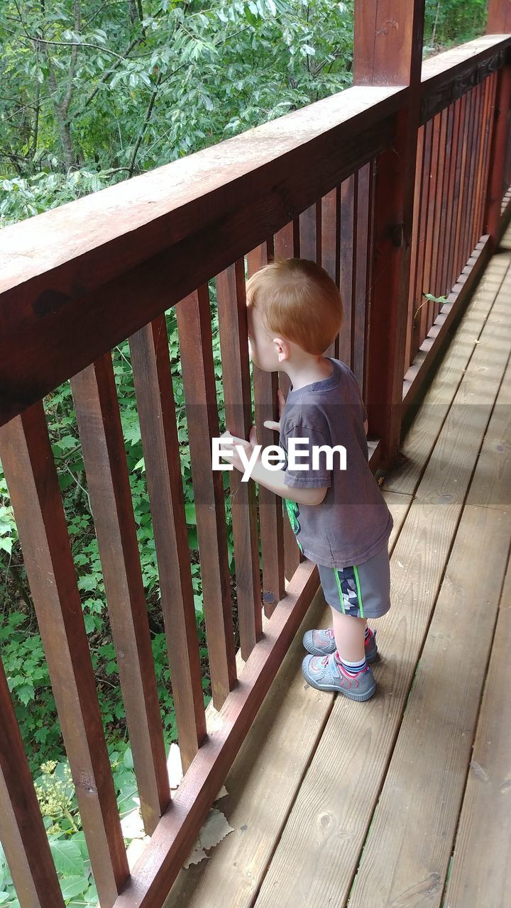 Full length of cute boy standing by railing