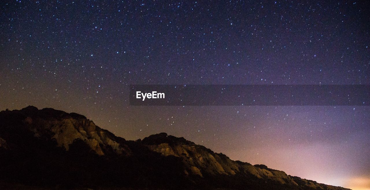 Low angle view of mountain against star field sky at night