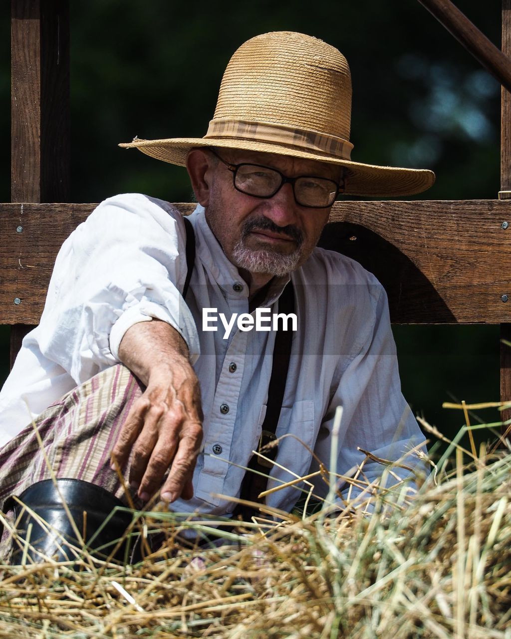 MAN WEARING HAT SITTING OUTDOORS