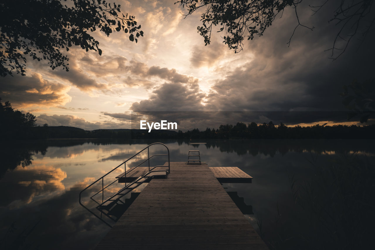 Pier over lake against sky during sunset