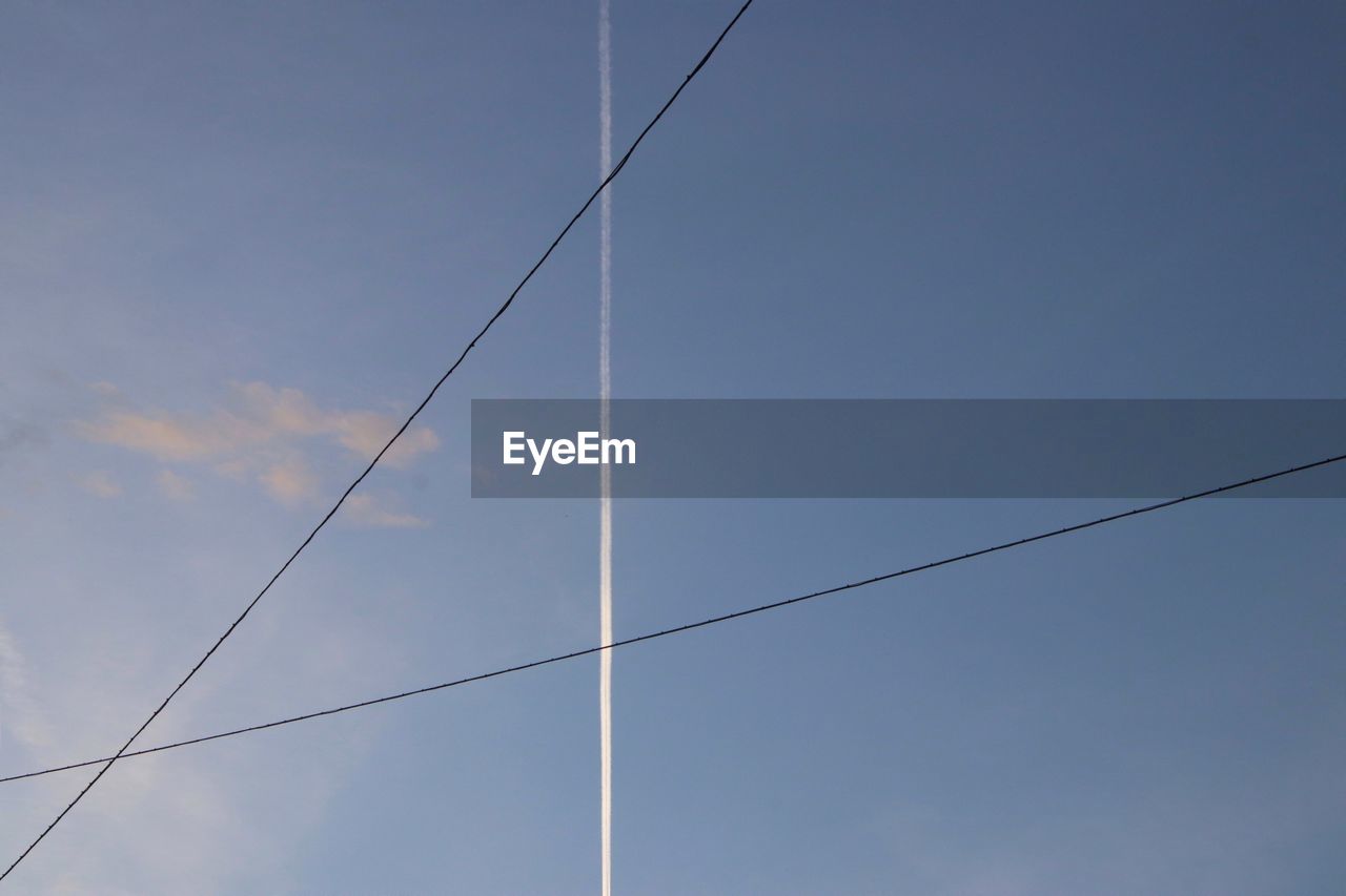 Low angle view of power lines against blue sky